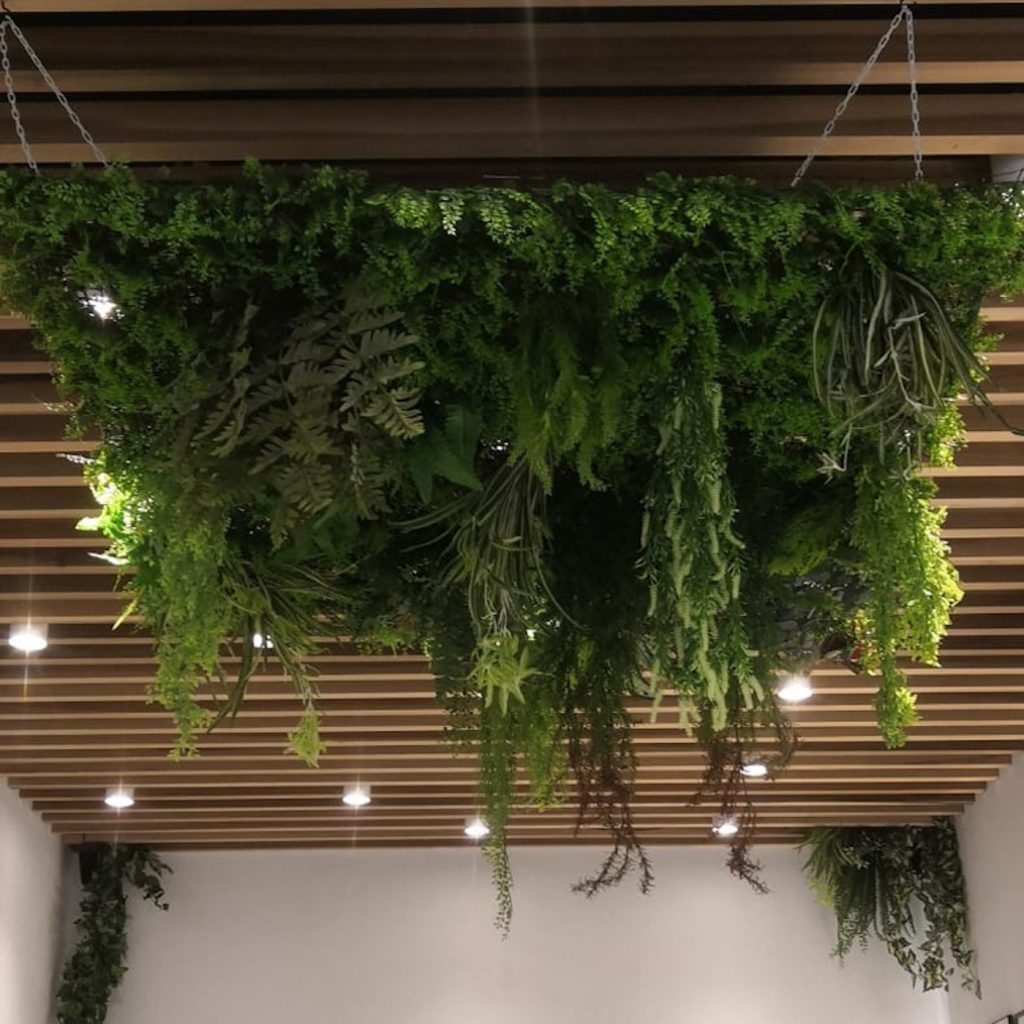 artificial hedge tile with added foliage hanging from a ceiling in a restaurant