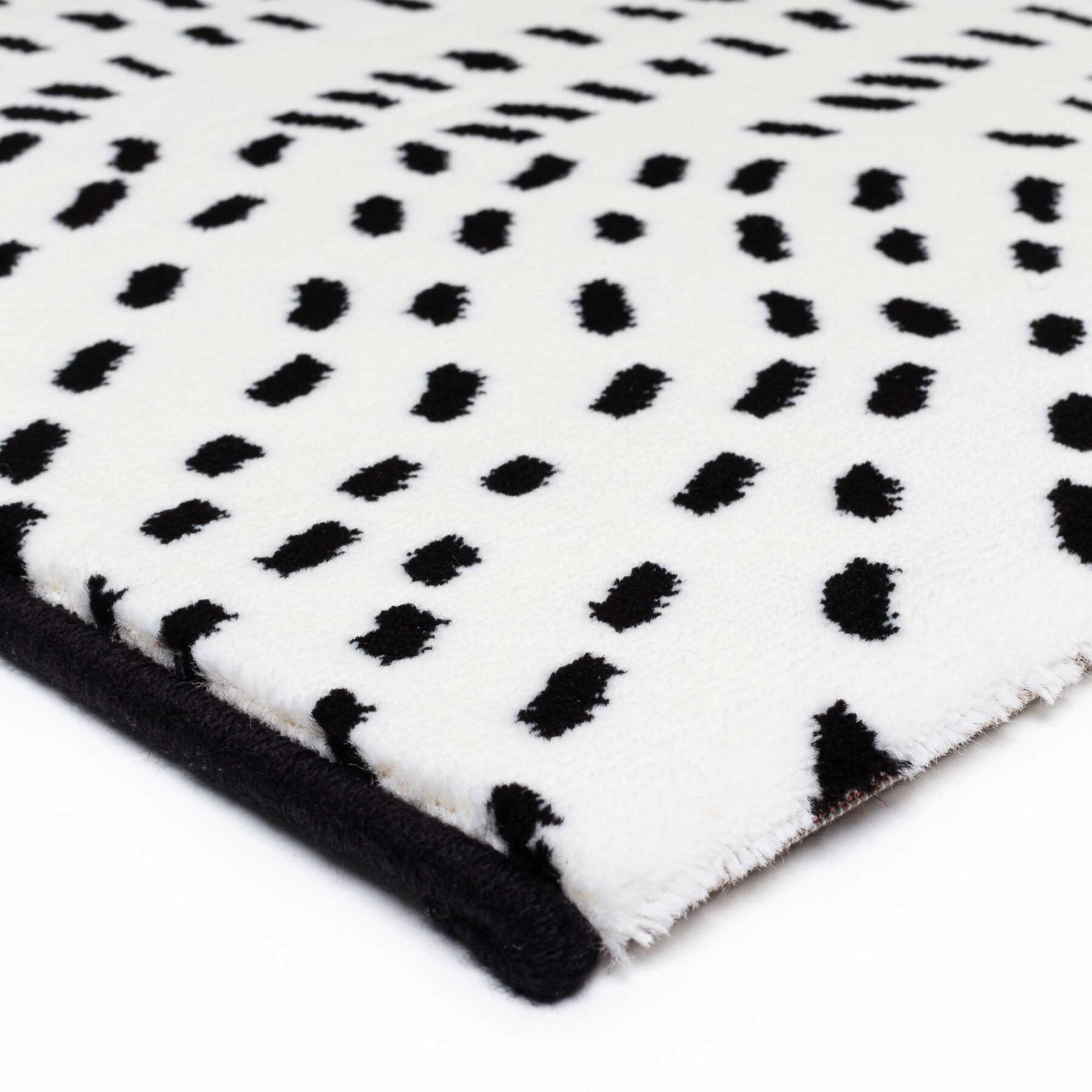 close up of Tiago indoor rug spotted design white background with black spots