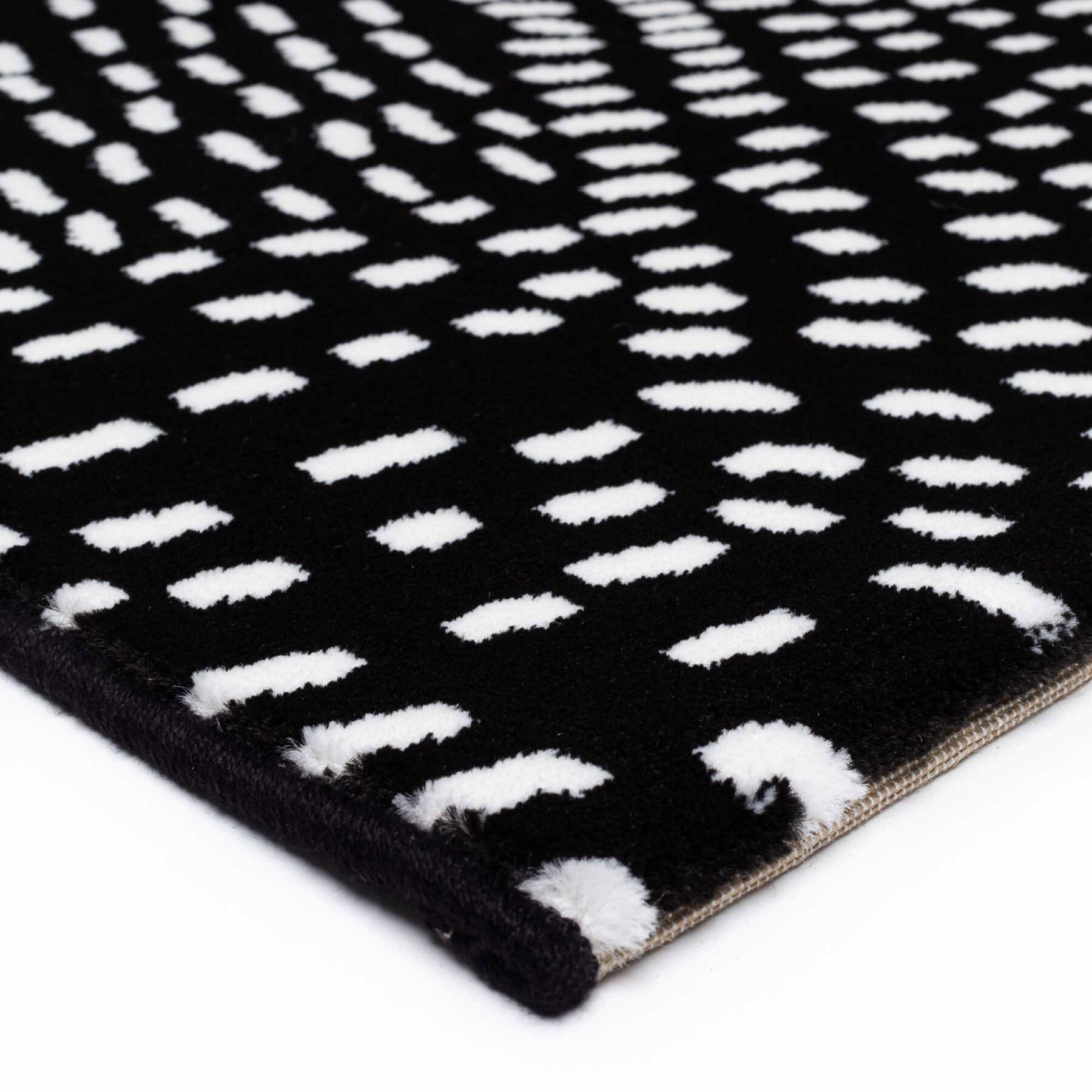 edging of Tiago indoor rug spotted design black background with white spots